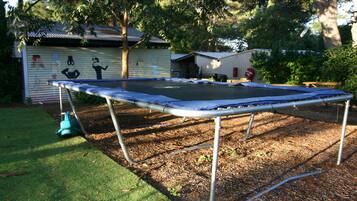 A trampoline in a backyard with a shed and trees in the background.