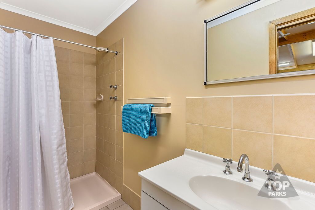 A bathroom with a shower, a sink, and a towel rack.