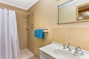 Baño con ducha, lavabo y barra para toallas.