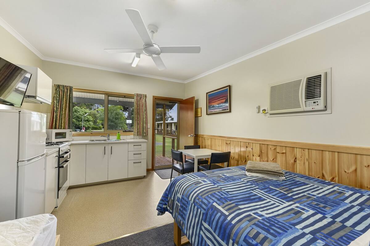 Quarto com cama, escrivaninha, pia e janela.