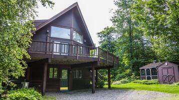 Une cabane en bois à deux étages, dotée d’un balcon et entourée d’une végétation luxuriante.