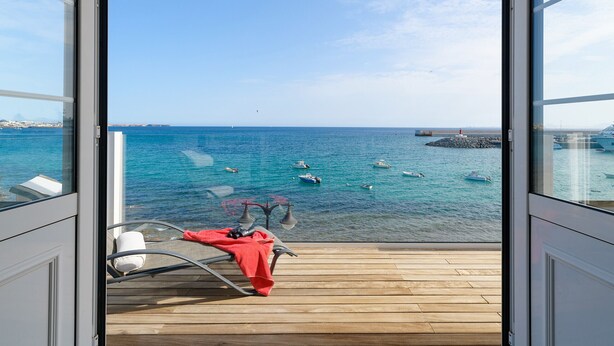 A balcony with a view of the sea, boats, and a distant shoreline. - Casa Lola, Sea Front Apartment in Playa Blanca (Playa Blanca)