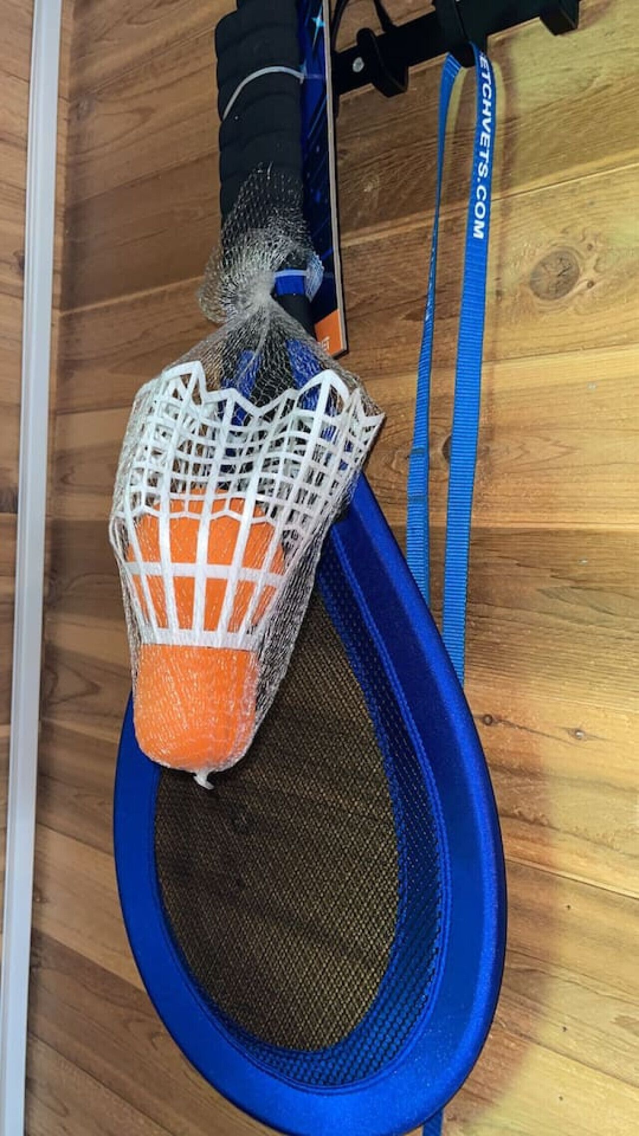 Un trampoline bleu avec un filet fixé à un mur.