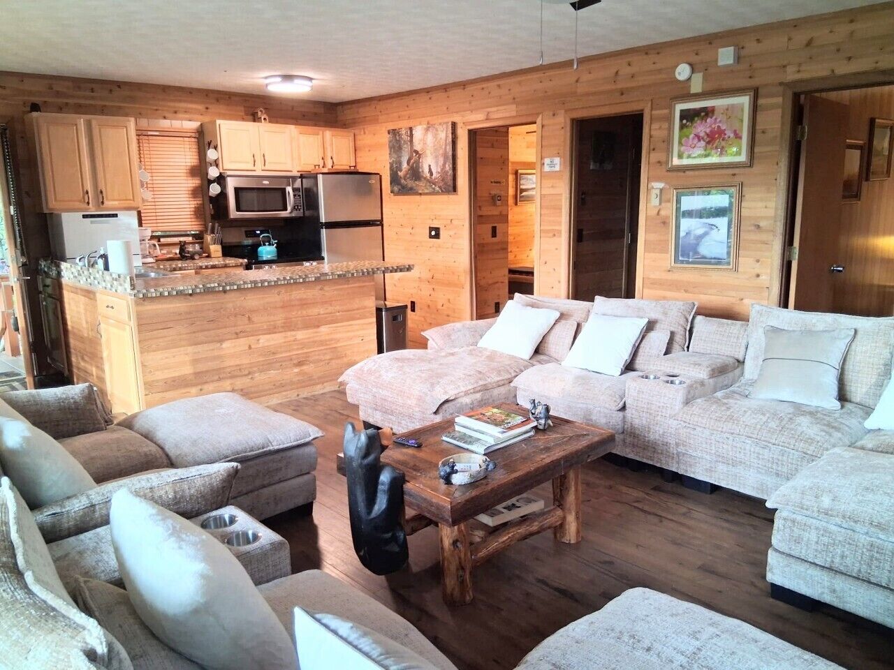Un acogedor interior de cabaña con sala de estar, sofá, mesa de centro y kitchenette.