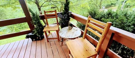 Une terrasse en bois avec un banc et une table, entourée de verdure.