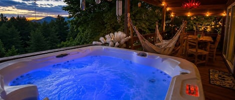 Un bain à remous avec un éclairage bleu, entouré de meubles en bois et illuminé de guirlandes lumineuses.