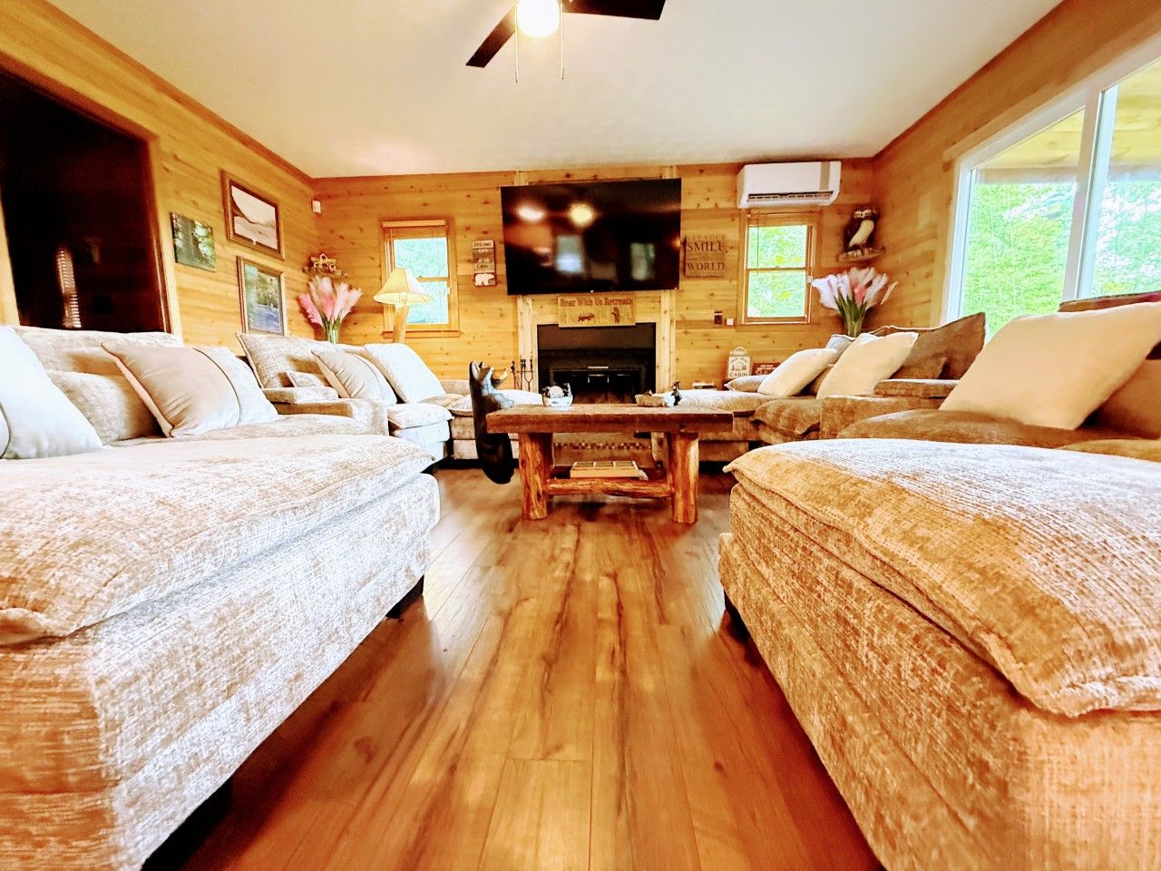 L’intérieur d’un chalet chaleureux, avec une cheminée, des murs en bois et un téléviseur fixé au-dessus.