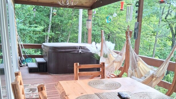 An outdoor wooden deck with a hot tub, hammocks, and a table with placemats. - Mountain View Cabin Hot Tub,Wifi,Casino (Whittier)