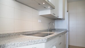 A modern kitchen with a granite countertop, stainless steel sink, and white cabinetry.