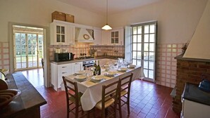 A spacious kitchen with a dining table set for four, white cabinetry, and a brick fireplace. - Villa in Il Passaggio with 5 bedrooms sleeps 10 (Il Passaggio)