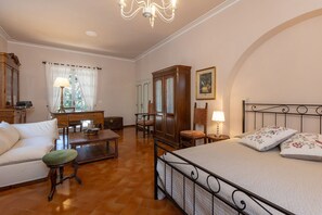 Ein Schlafzimmer mit Bett, Schreibtisch, Stuhl, Kleiderschrank und einem Fenster mit Vorhängen.