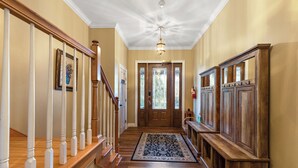 A hallway with wooden flooring, a staircase with white balusters, a patterned rug, and a wooden bench. - Mountain Family Lodge: A spacious 7-bedroom retreat in Boone, NC, perfect for 28 guests. (Boone)
