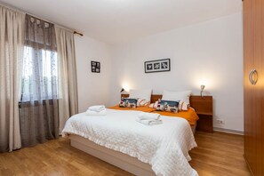A hotel room with a bed, curtains, a headboard, wall-mounted lights, and a wooden wardrobe.