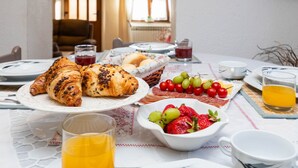 Une table de petit-déjeuner avec des croissants, des raisins, des fraises et du jus de fruits.