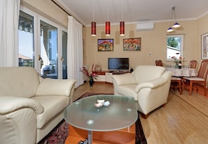 A living room with a glass coffee table, two sofas, a TV, and artwork on the wall.