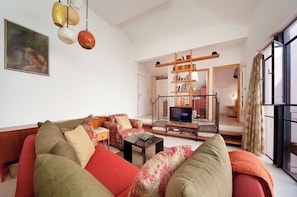 A living room with a sofa set, a television, and a bookshelf.