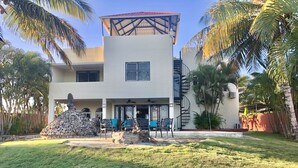 A two-story house with a covered patio, outdoor seating, and a stone sculpture. - Villa Vista Mar (Sosúa)