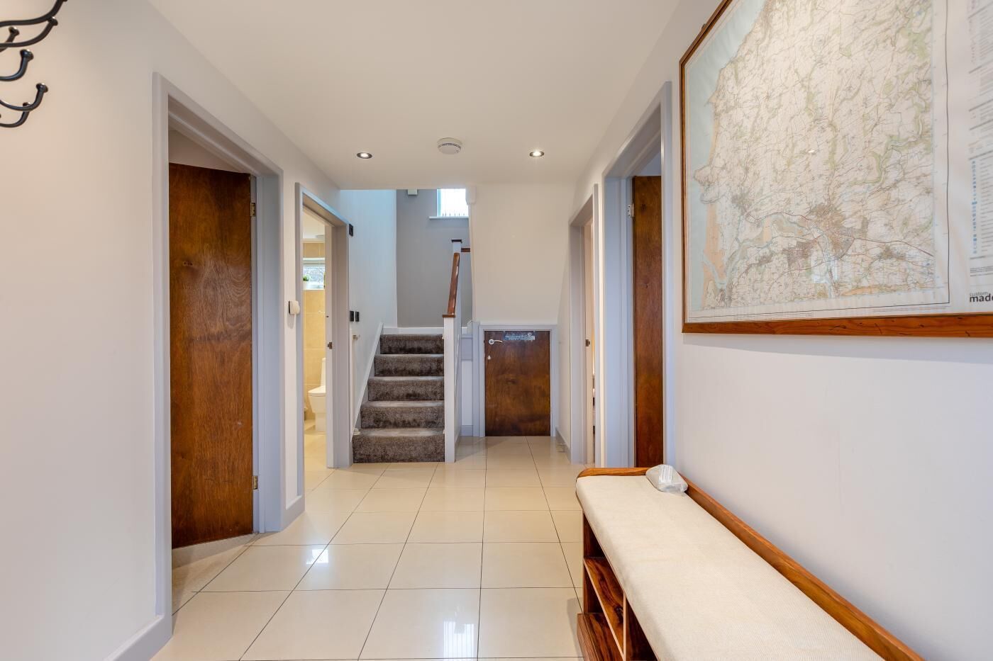 A hallway with a wooden bench, a staircase, and a map on the wall.