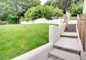 Steps lead to an entrance surrounded by lush greenery.