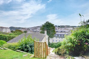 A residential area with a view of a town, a wooden gate, and a hill in the background.