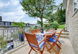 Relax on the furnished outdoor space with a table and chairs, surrounded by lush greenery and a scenic view.