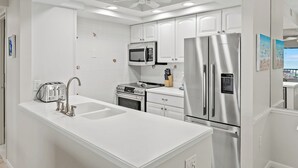 Een moderne keuken met witte kasten, roestvrijstalen apparatuur en een centraal eiland met een spoelbak.