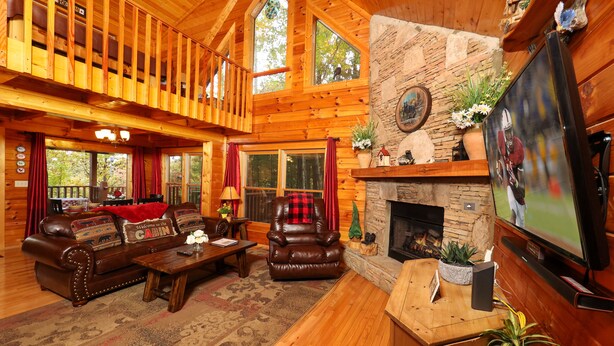 A log cabin interior with a fireplace, leather furniture, and a television. - Beautiful Mtn Views! Close to Dollywood & Attractions - Pool, Putt Putt, Tennis (Sevierville)