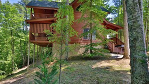 A wooden cabin with a balcony, surrounded by trees. - Beautiful Mtn Views! Close to Dollywood & Attractions - Pool, Putt Putt, Tennis (Sevierville)