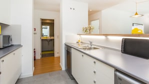 Una cucina moderna con mobili bianchi, lavello in acciaio inox e microonde.