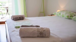 Una cama bien hecha con toallas enrolladas y una almohada verde.