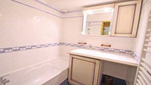 A bathroom with a bathtub, a sink, and a mirror above the sink.