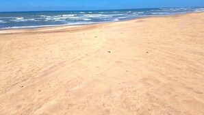 A wide sandy beach with gentle waves.