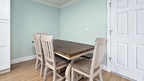 Une salle à manger avec une table en bois et quatre chaises, des murs bleu clair et une porte blanche.