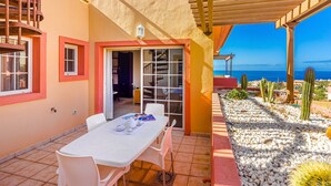A patio with a table and chairs, a pergola, and a view of the sea. - TERRAZAS DEL DUQUE II COSTA ADEJE (Costa Adeje)