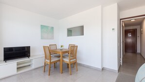 Un coin repas avec un téléviseur, des chaises en bois, une petite table et un tableau accroché au mur.
