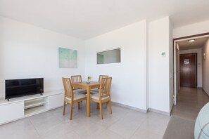 Un coin repas avec un téléviseur, des chaises en bois, une petite table et un tableau accroché au mur.