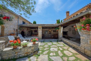 Un bâtiment en pierre doté d’un patio couvert, d’un espace extérieur aménagé pour s’asseoir et d’une cheminée.