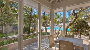 A covered patio with a view of a swimming pool and surrounding greenery. - Pool Front Cottage, Ground Floor, Rare One-Bedroom, Walk to the Beach (Miramar Beach)