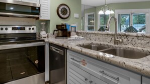 A kitchen with a stove, oven, dishwasher, and double sink. - Pool Front Cottage, Ground Floor, Rare One-Bedroom, Walk to the Beach (Miramar Beach)