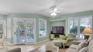 A living room with a television, a ceiling fan, and a sofa. - Pool Front Cottage, Ground Floor, Rare One-Bedroom, Walk to the Beach (Miramar Beach)