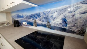 Une cuisine moderne avec une grande fenêtre donnant sur un paysage montagneux enneigé.