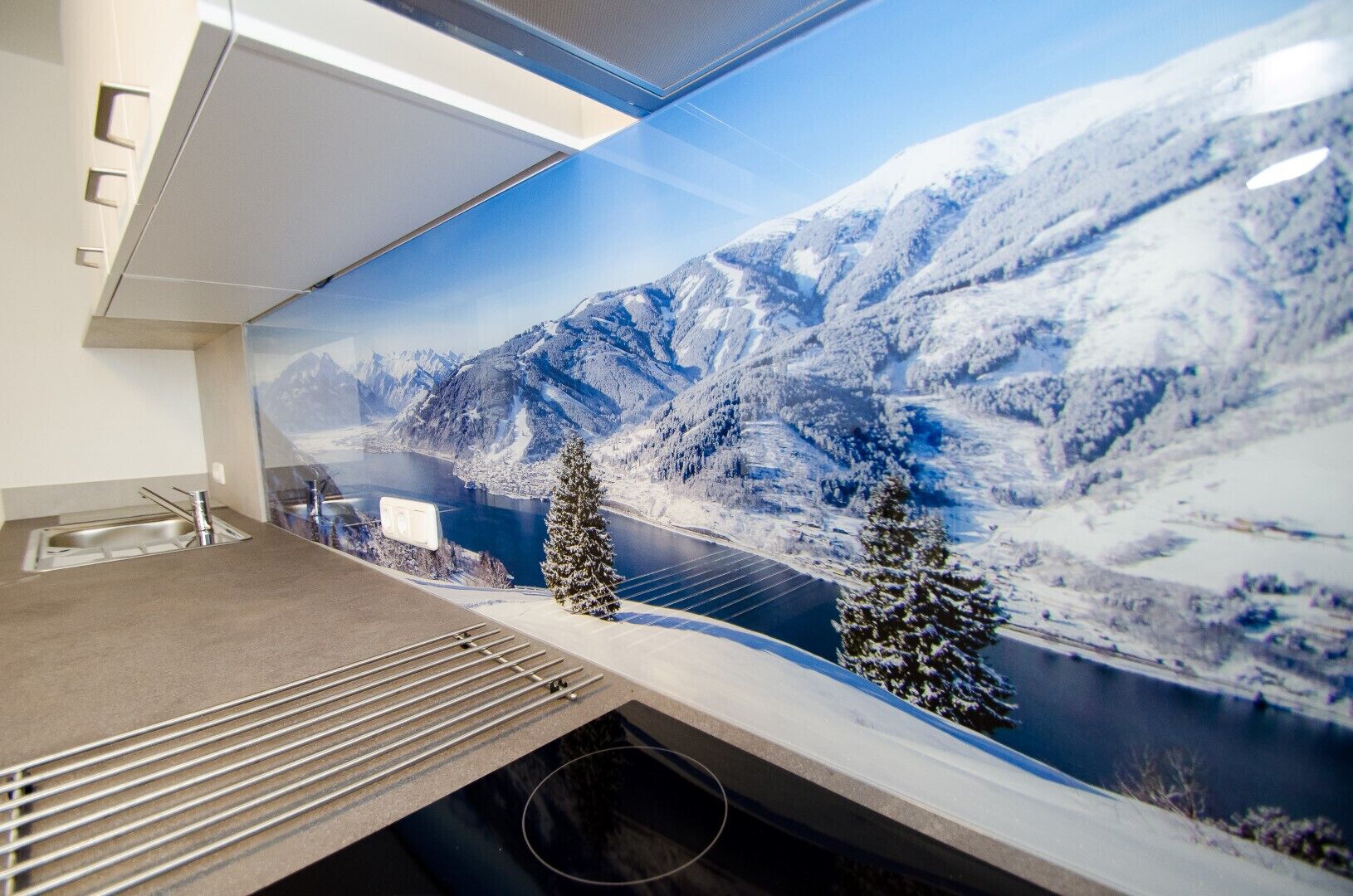 A kitchen with a large window overlooking a snowy mountain landscape.