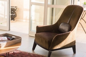 A brown upholstered armchair with a cushion, positioned in a room with a glass door leading outside.