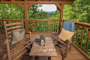 A wooden deck with two benches, a table, and a lantern.