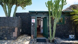 Edificio de piedra con una puerta verde, rodeado de cactus.