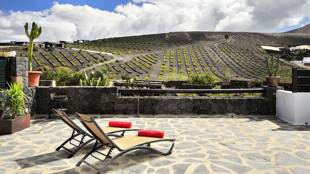 Una terraza con sillones de descanso y vistas a campos escalonados.
