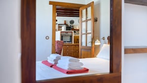 Una habitación de hotel con una cama, una puerta de madera y una cocina visible a través de la puerta.