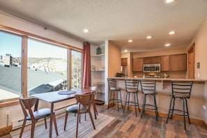 Uma cozinha moderna com uma ilha grande, banquetas de bar e uma área de jantar com mesa e cadeiras.