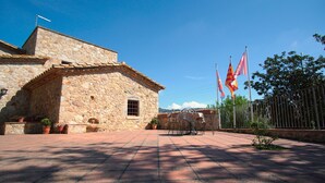 A stone building with a tiled roof, a small window, and a door. There are potted plants and a metal chair outside. - Molí d'en Tarrés.   Ideal house for families10 people. (Santa Cristina d'Aro)