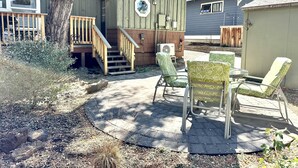A backyard with a wooden deck, outdoor seating, and a staircase leading to a covered area. - Aspen House- Sweet, Modern Downtown Cottage, 100+mbps Wifi, A/C, Walk Everywhere (Bend)